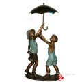 bronze boy and girl statues holding umbrella